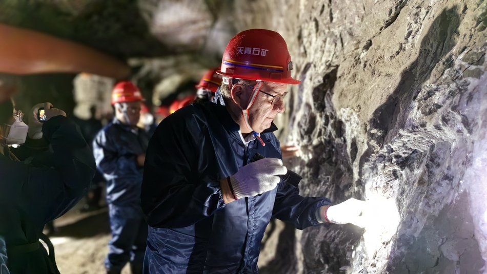 Prof. Langefeld betrachtete den Stoß (Wand) in einem untertägigen Bergwerk. Er trägt einen blauen Overall, einen roten Helm sowie weiße Handschuhe