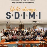 Gruppenfoto der Teilnehmerinnen und Teilnehmer des internationalen SDIMI-Meetings 2026 in Medellín in einem Konferenzraum, frontal aufgenommen. Vorne sitzen und stehen mehrere Reihen von Personen mit Namensschildern, im Hintergrund sind weitere Konferenzgäste zu sehen; oben im Bild ist ein gestalteter Schriftzug mit dem Motto „Today is not the end of SDIMI 2026 … knowledge unites the world, the future is transformed“ und groß „SDIMI 2026“, der den Abschluss der Tagung zum Thema nachhaltiger Bergbau hervorhebt.